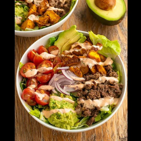 Two bowls of salad with lettuce, tomatoes, and avocado.