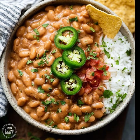 A bowl of beans with jalapenos and rice.