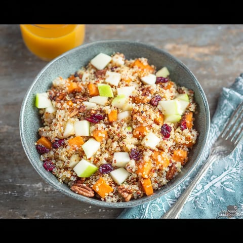 A bowl of food with a fork and a glass of orange juice.
