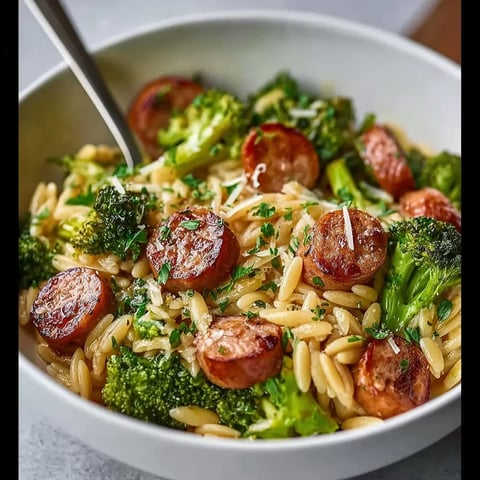 A bowl of pasta with sausage and broccoli.